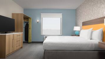 Une chambre d’hôtel équipée d’un lit, d’une télévision, d’une armoire, d’une fenêtre et d’une table de chevet avec une lampe.