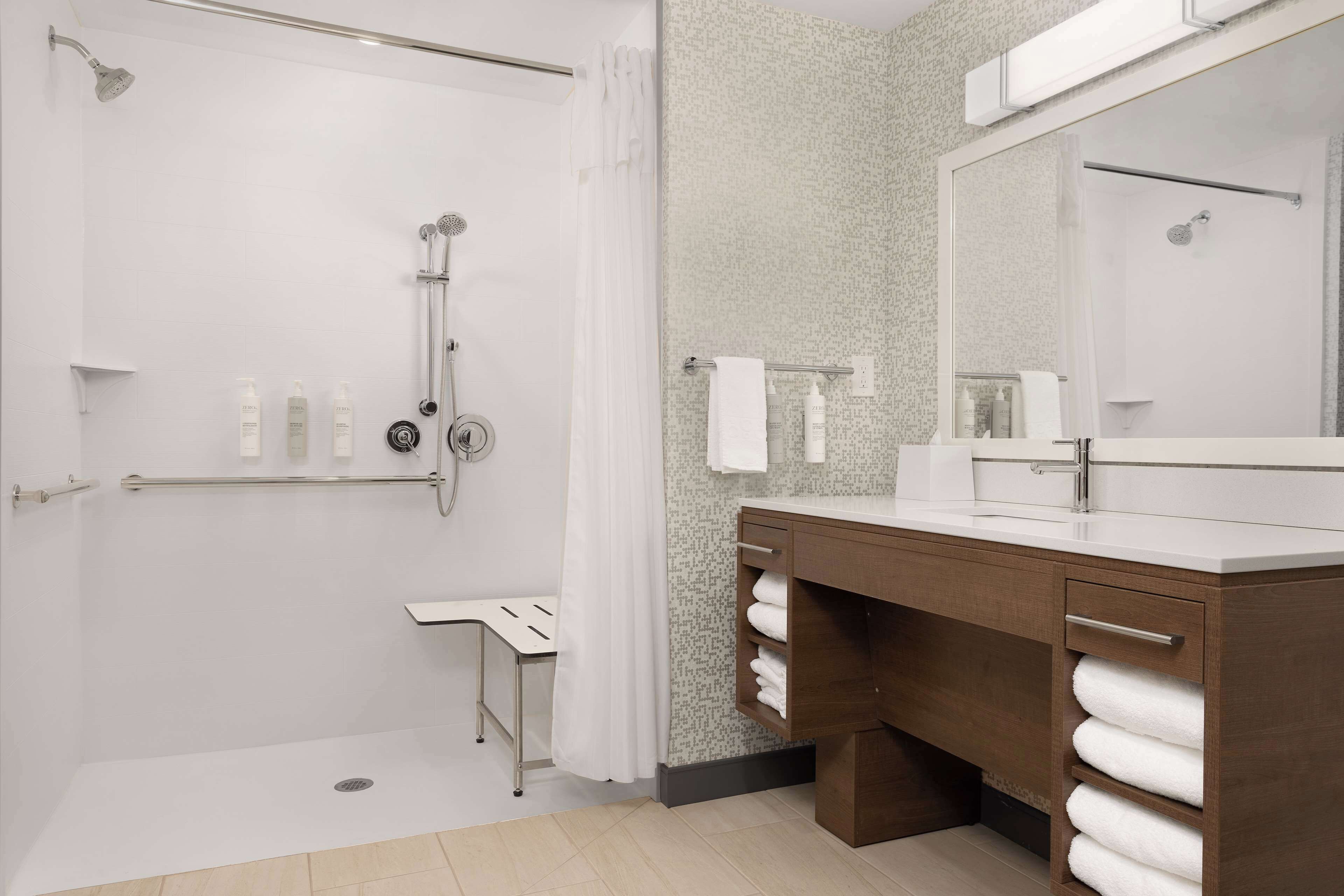 A modern bathroom with a walk-in shower, a vanity with a large mirror, and a towel rack.