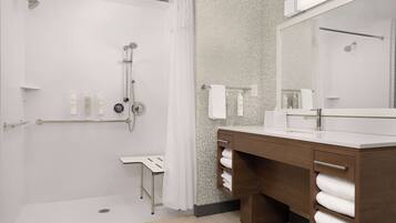 A modern bathroom with a walk-in shower, a vanity with a large mirror, and a towel rack.