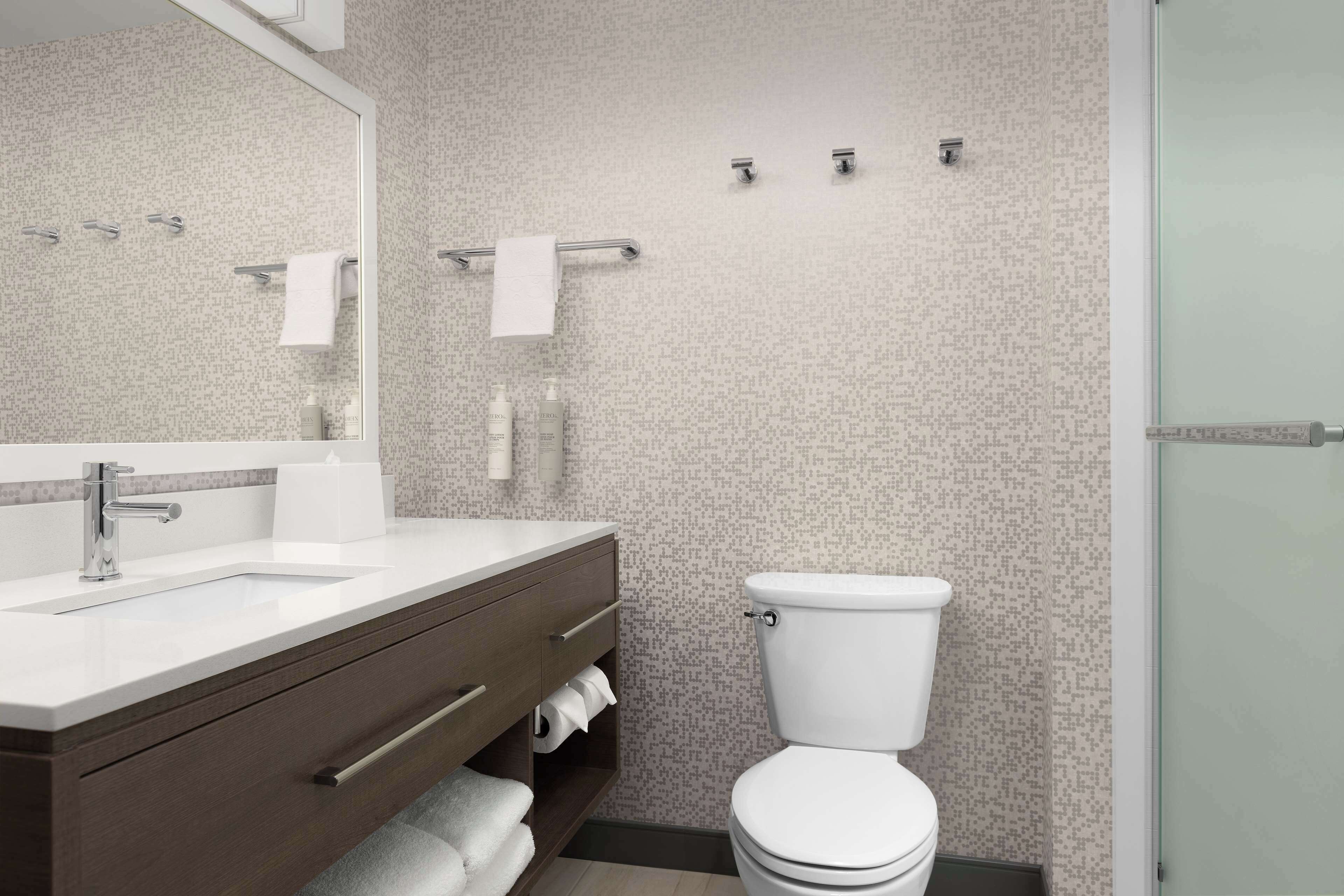 A modern bathroom with a white sink, vanity, and toilet.