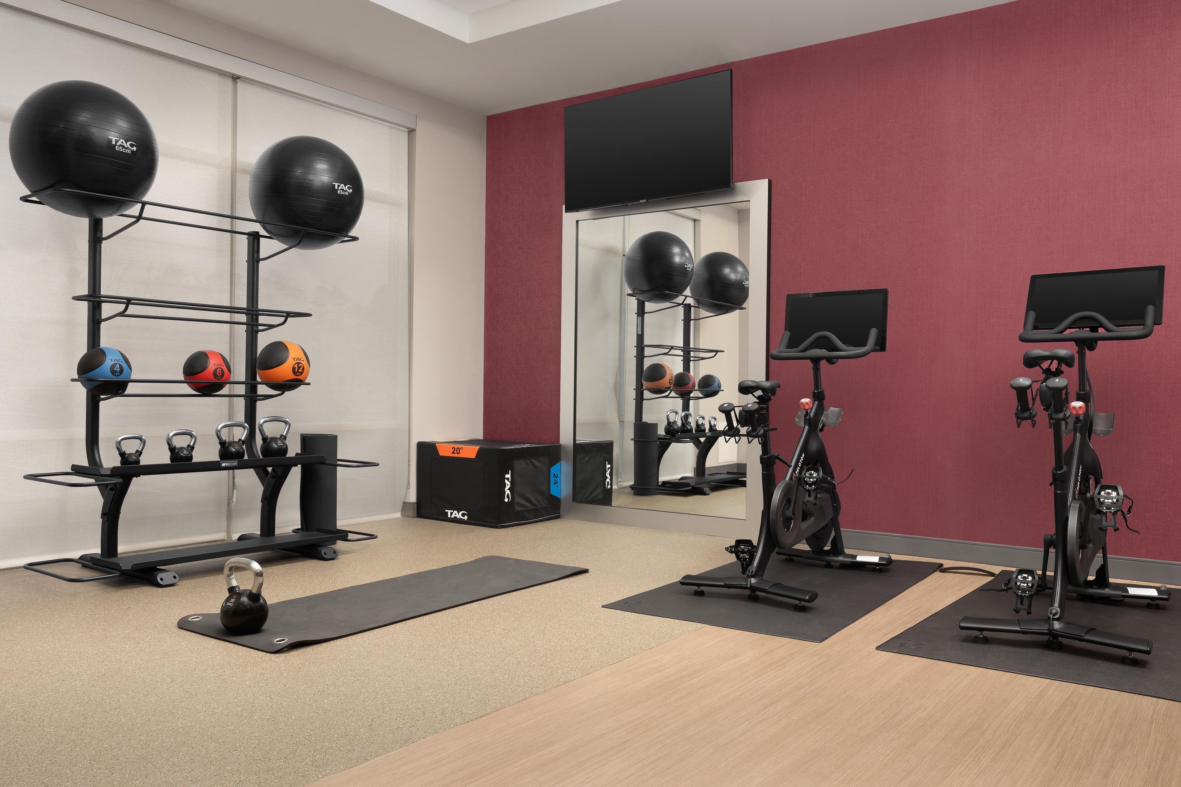 Academia com equipamentos de ginástica, incluindo kettlebells, bolas de medicina e uma bicicleta ergométrica.