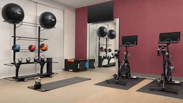 Academia com equipamentos de ginástica, incluindo kettlebells, bolas de medicina e uma bicicleta ergométrica.