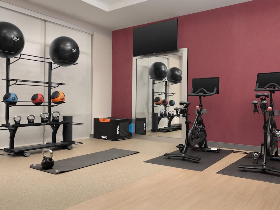 Un gimnasio con equipamiento de ejercicio, incluyendo pesas rusas, balones medicinales y una bicicleta estática.