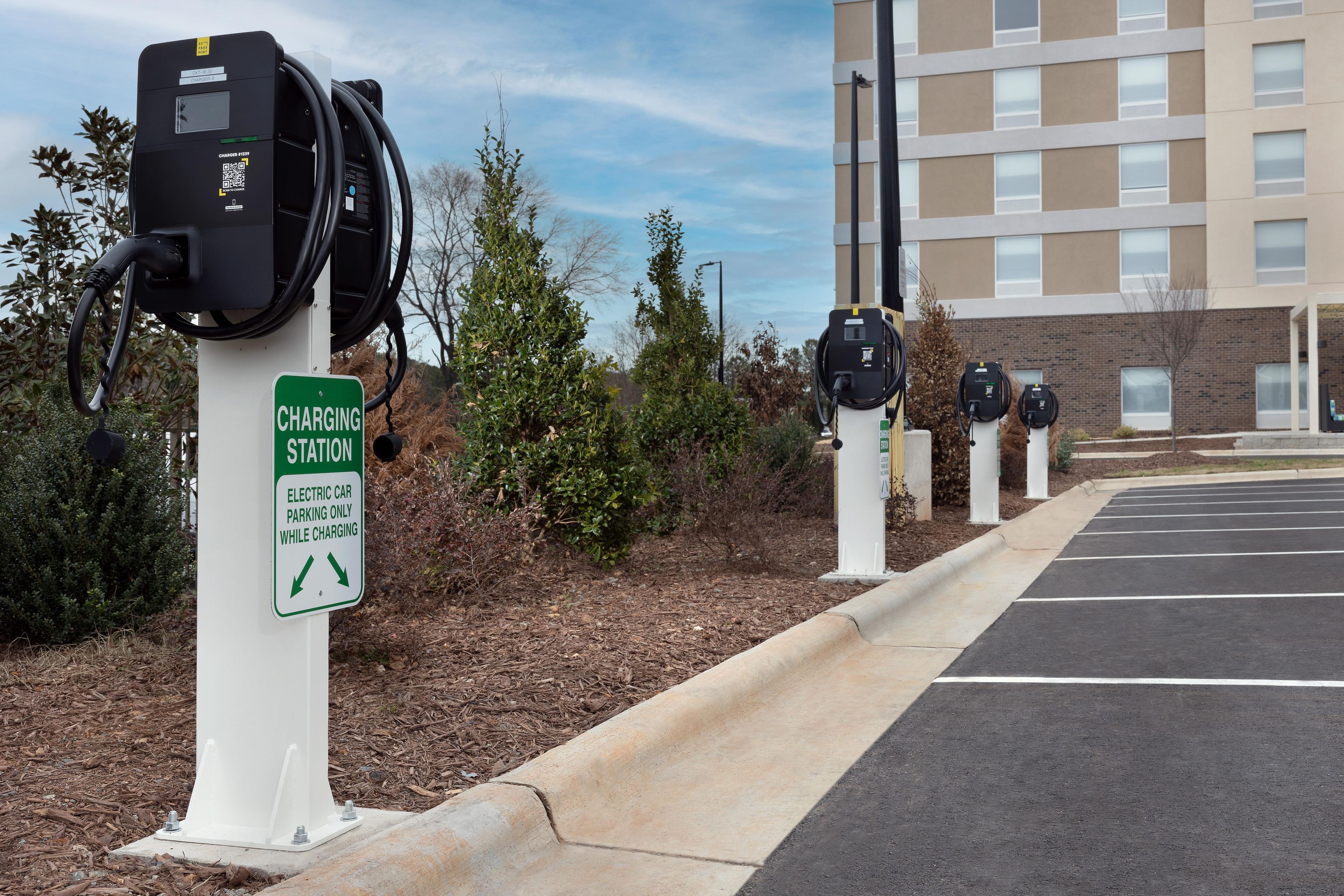 A row of electric vehicle charging stations with a sign indicating parking is only allowed while charging.