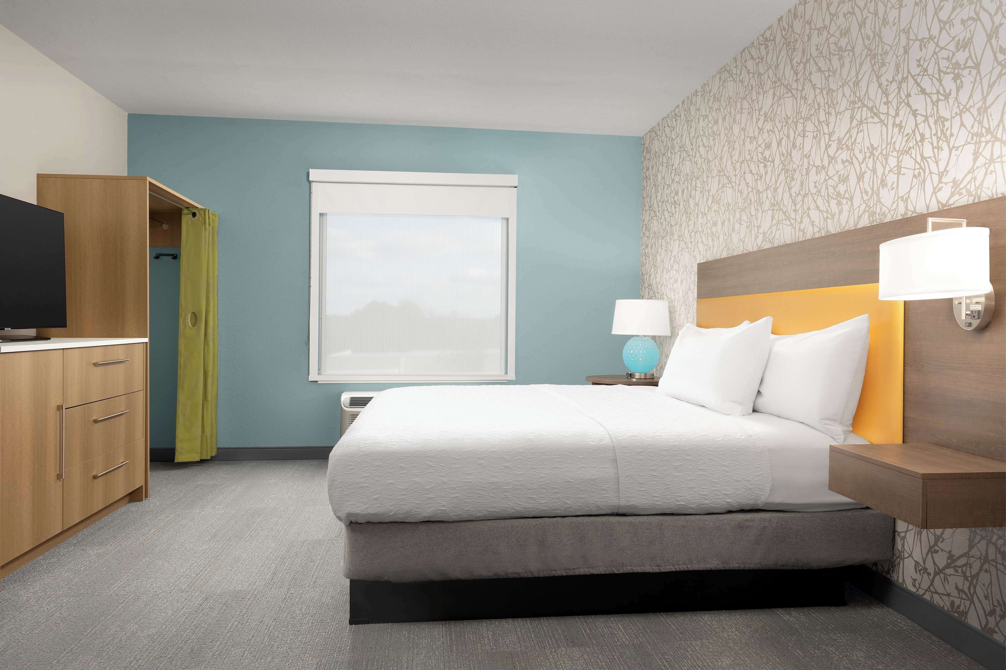 A hotel room with a bed, a TV, a wardrobe, and a window with a view.