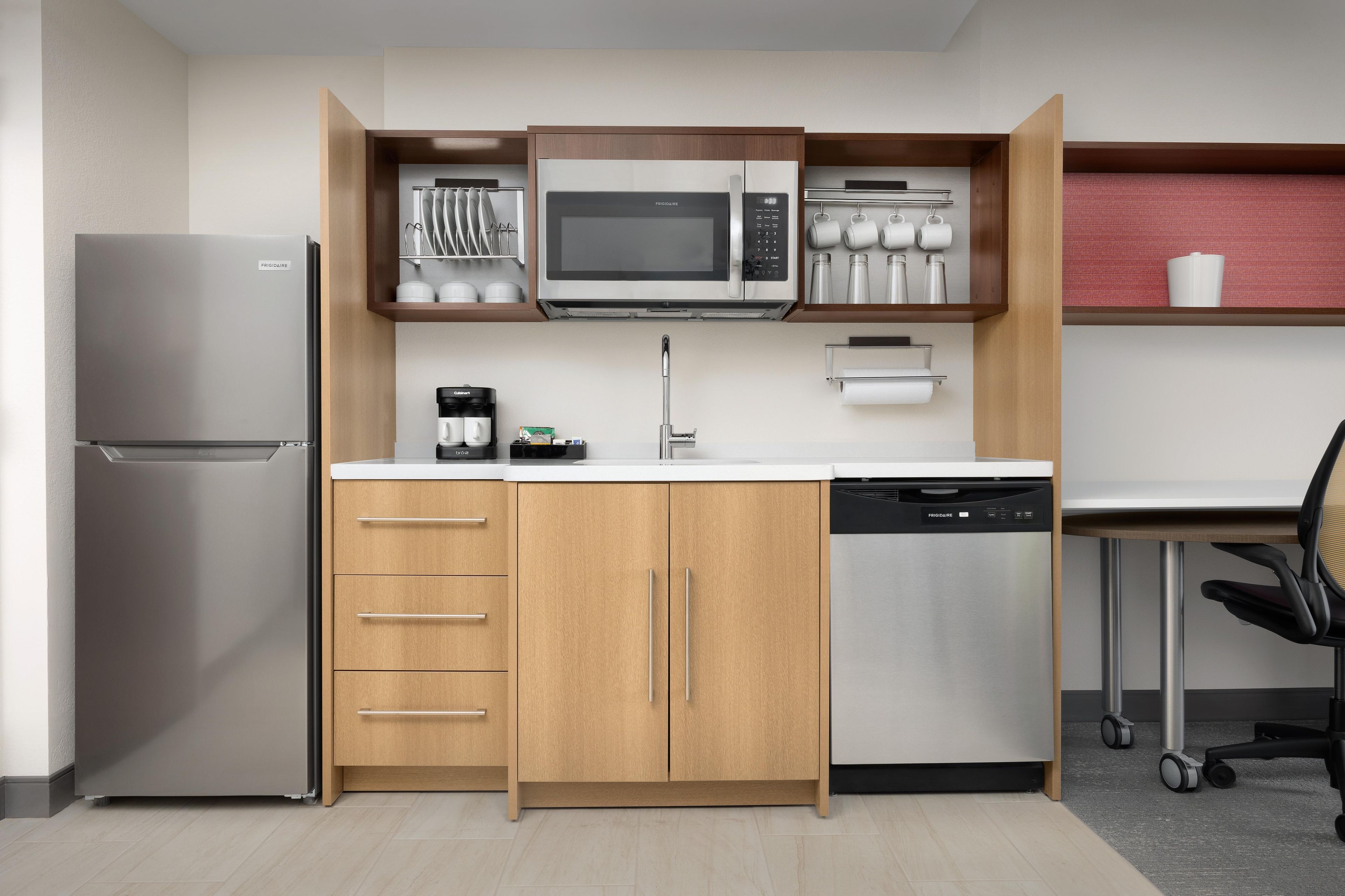 Una cocina compacta equipada con refrigerador, microondas, cafetera y lavavajillas.