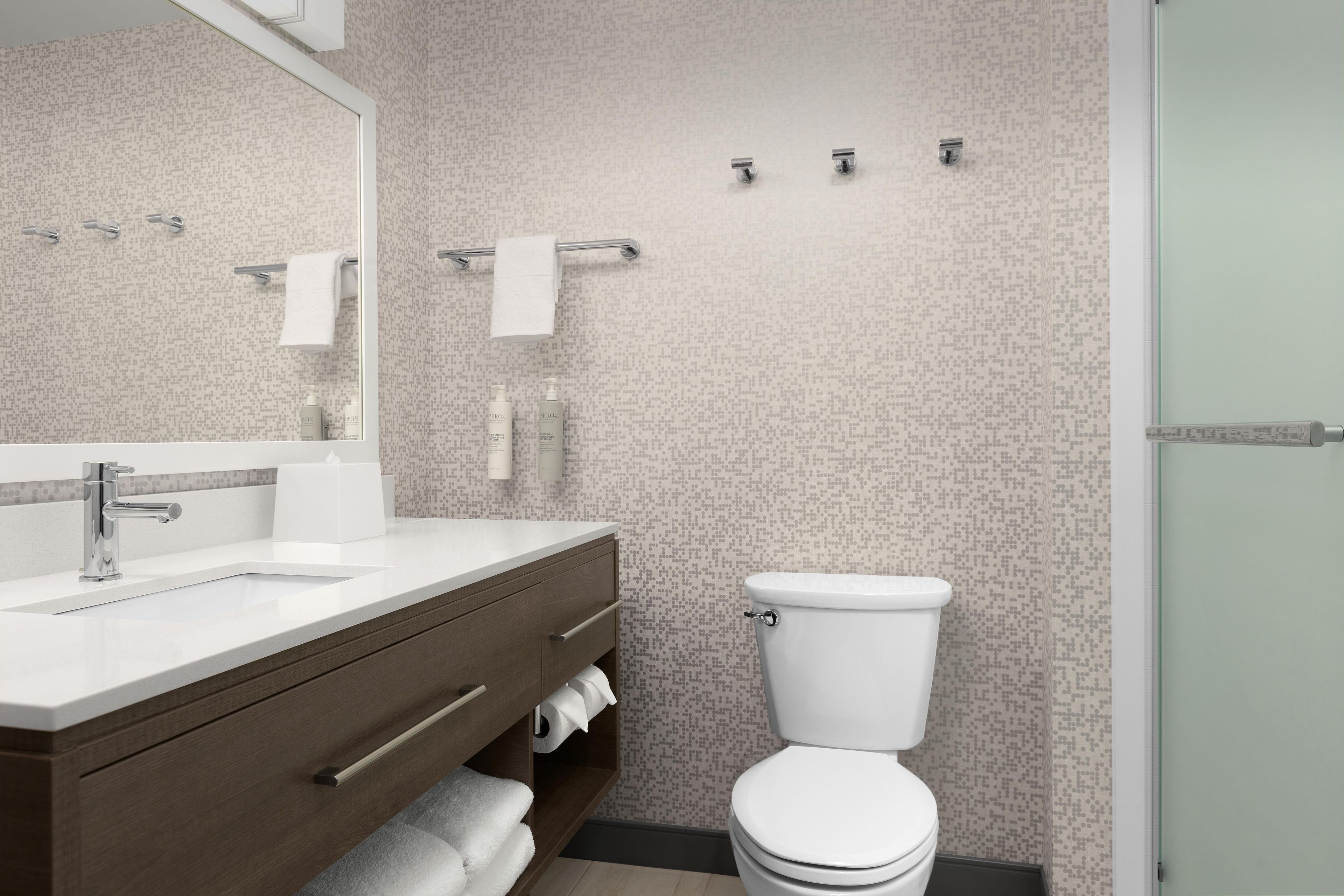 A modern bathroom with a white sink, a mirror, a toilet, and a towel rack.