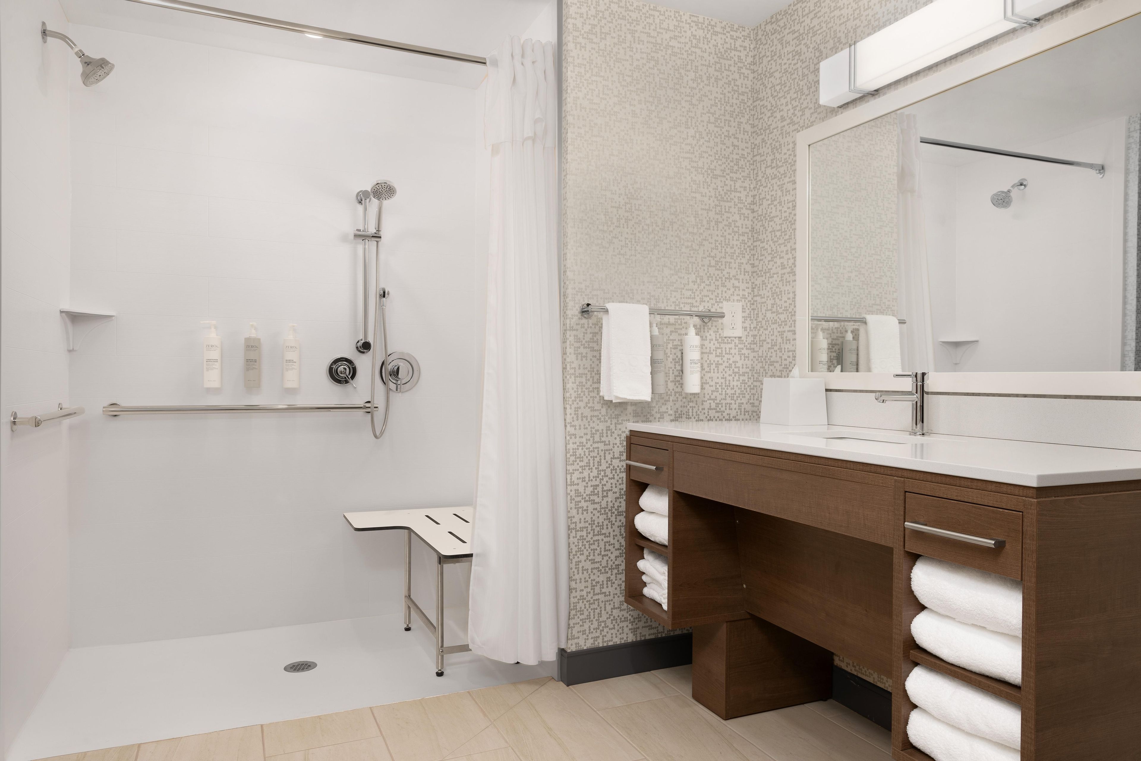 A modern bathroom with a shower, a vanity with a mirror, and a towel rack.