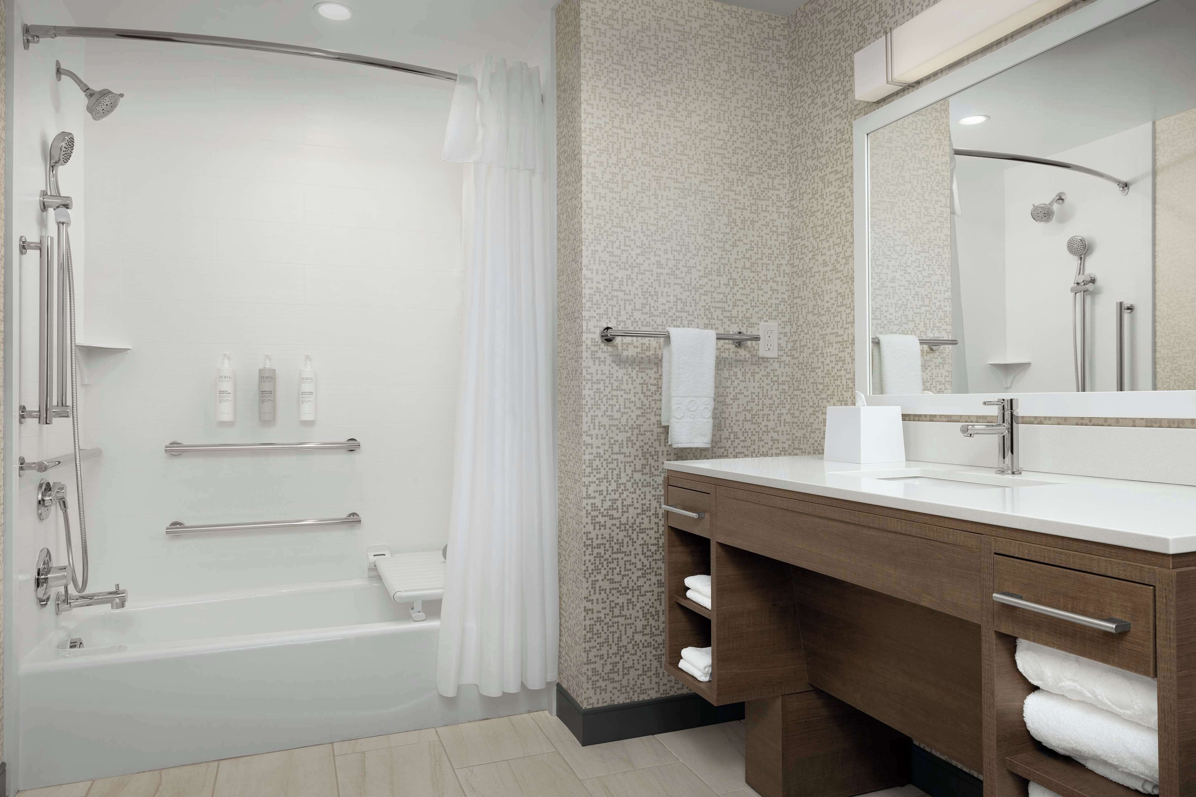 A modern bathroom with a glass-enclosed shower, a wooden vanity with a mirror, and a white sink.