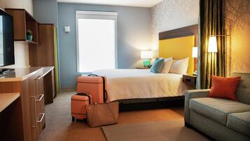 Une chambre d’hôtel avec un lit, un canapé, un bureau et une valise.
