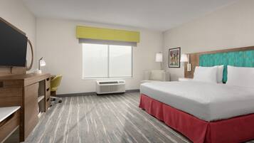 A hotel room with a bed, desk, chair, air conditioning unit, and a window with a yellow blind.