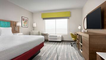 A hotel room with a bed, a desk, a chair, a television, and a window with a view.