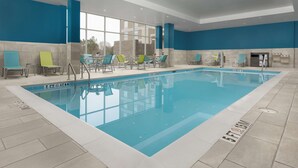 An indoor swimming pool with clear blue water, surrounded by lounge chairs and a tiled floor. - Hampton Inn & Suites Durham University Medical Center (Durham)