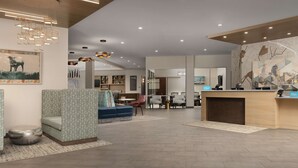 A modern hotel lobby with a reception desk, seating area, and a cityscape mural on the wall. - Hampton Inn & Suites Durham University Medical Center (Durham)