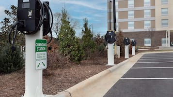 Un área de estacionamiento con estaciones de carga para coches eléctricos y un cartel que indica que el estacionamiento solo está permitido durante la carga.