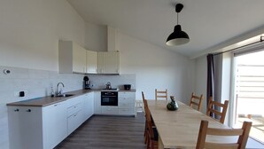 Een moderne keuken met witte kasten, een houten aanrecht en een eethoek met een houten tafel en stoelen.