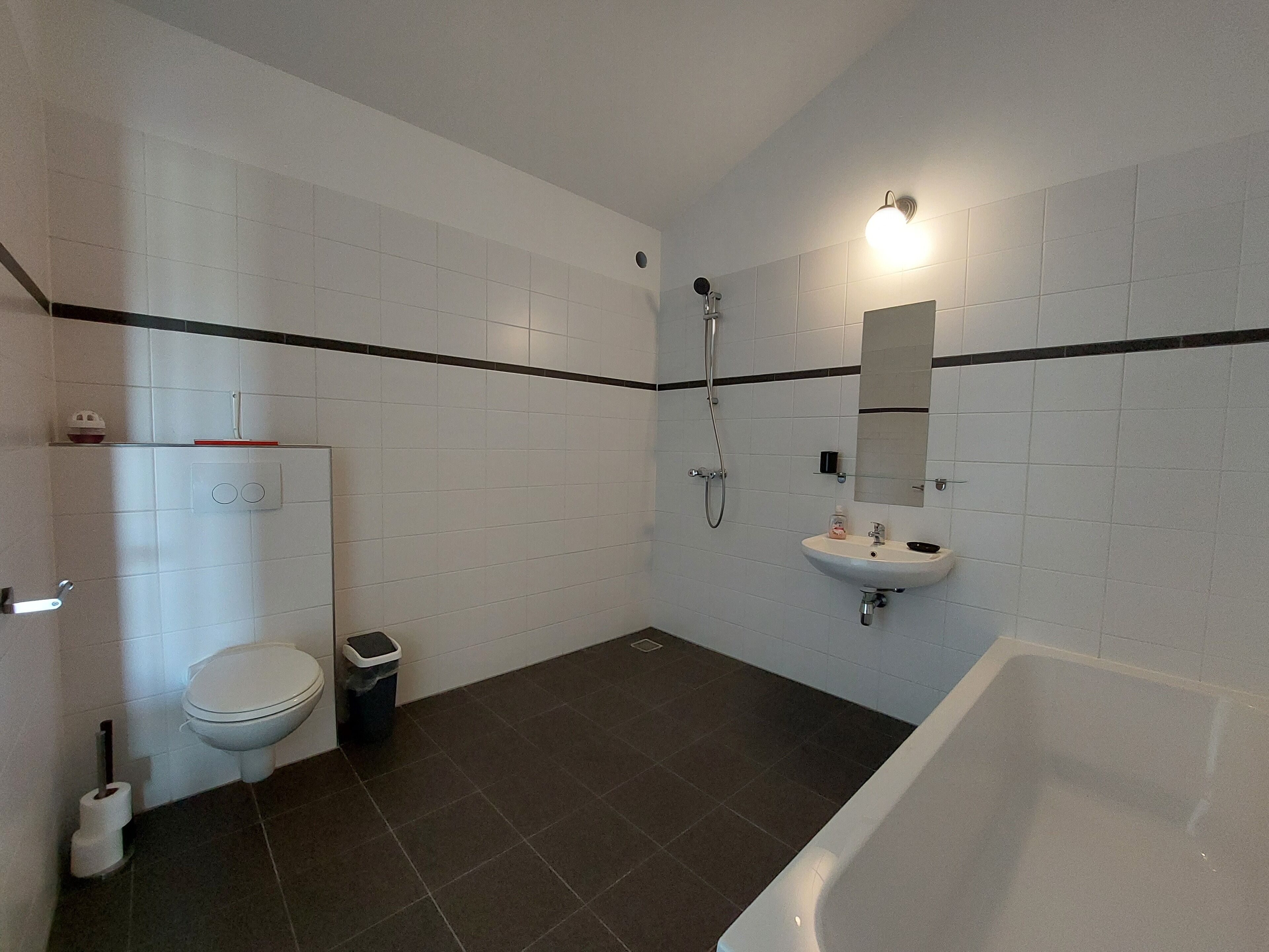 Un bagno con il water, bidet, cestino e vasca da bagno.
