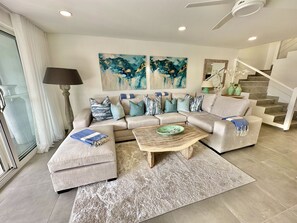 A living room with a sectional sofa, a coffee table, and two abstract paintings on the wall.
