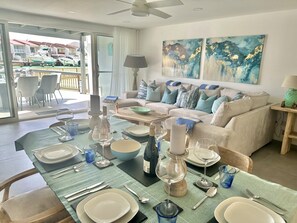 A dining area with a table set for four, a sofa, and two abstract paintings on the wall.
