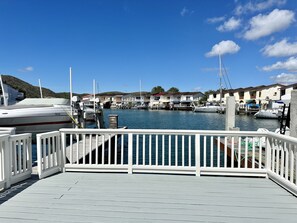 Un puerto deportivo con barcos amarrados, una terraza de madera y edificios al fondo.