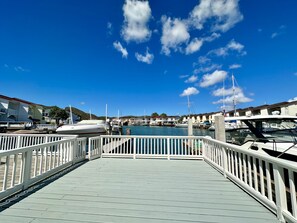 A marina with boats docked, a wooden deck, and buildings in the background. - Enchanting Waterfront Villa (Jolly Harbour)