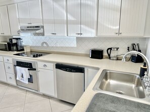 A modern kitchen with white cabinetry, stainless steel appliances, and a granite countertop. - Enchanting Waterfront Villa (Jolly Harbour)