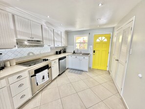 Una cocina moderna con armarios blancos, una estufa de acero inoxidable y una puerta amarilla.