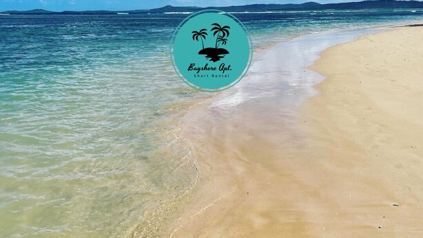 Una playa con agua turquesa cristalina y el logotipo de Bayhore Apt. Short Rental.
