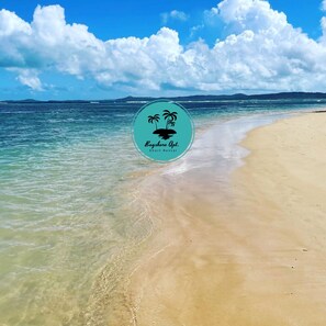 Uma praia com águas turquesa cristalinas e o logotipo da Bayhore Apt. Aluguel de Curta Duração.