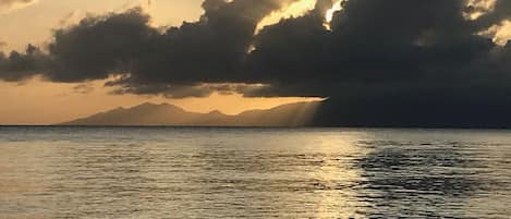 Un atardecer sobre un cuerpo de agua con montañas al fondo.