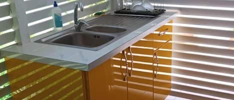 A kitchen with a sink, two cabinets, and a dish rack.