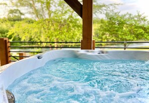 Un bain à remous doté d’une structure en bois au-dessus, entouré de verdure.