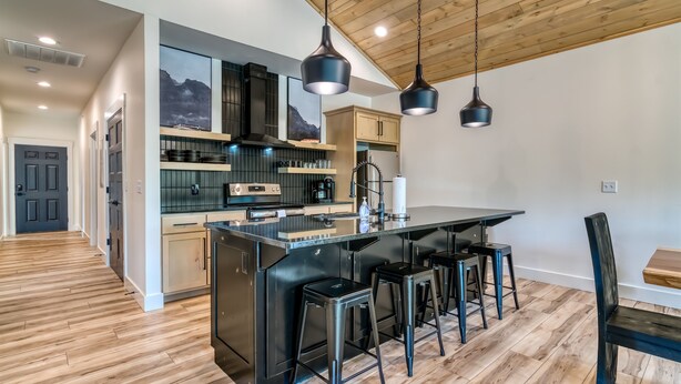 A modern kitchen with a central island, bar stools, and pendant lighting. - Lakefront, Amazing LakeView, Private Hot Tub! (Hollister)