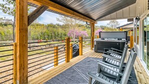 A covered deck with a grill, seating, and a view of a forested area. - Lakefront, Amazing LakeView, Private Hot Tub! (Hollister)