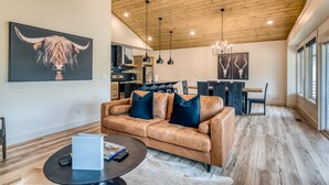 A spacious living area with a leather sofa, a dining table, and a kitchen in the background. - Lakefront, Amazing LakeView, Private Hot Tub! (Hollister)