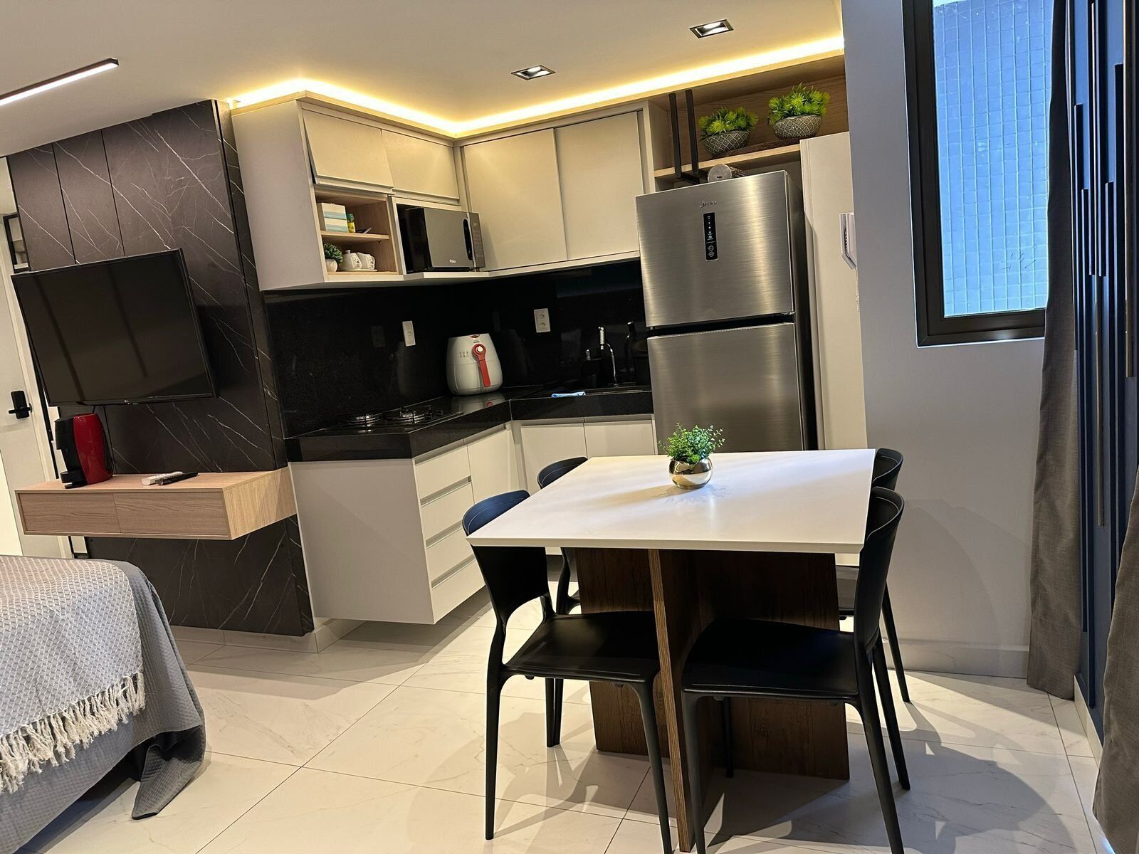 Una cocina moderna con comedor, televisor integrado y refrigerador.