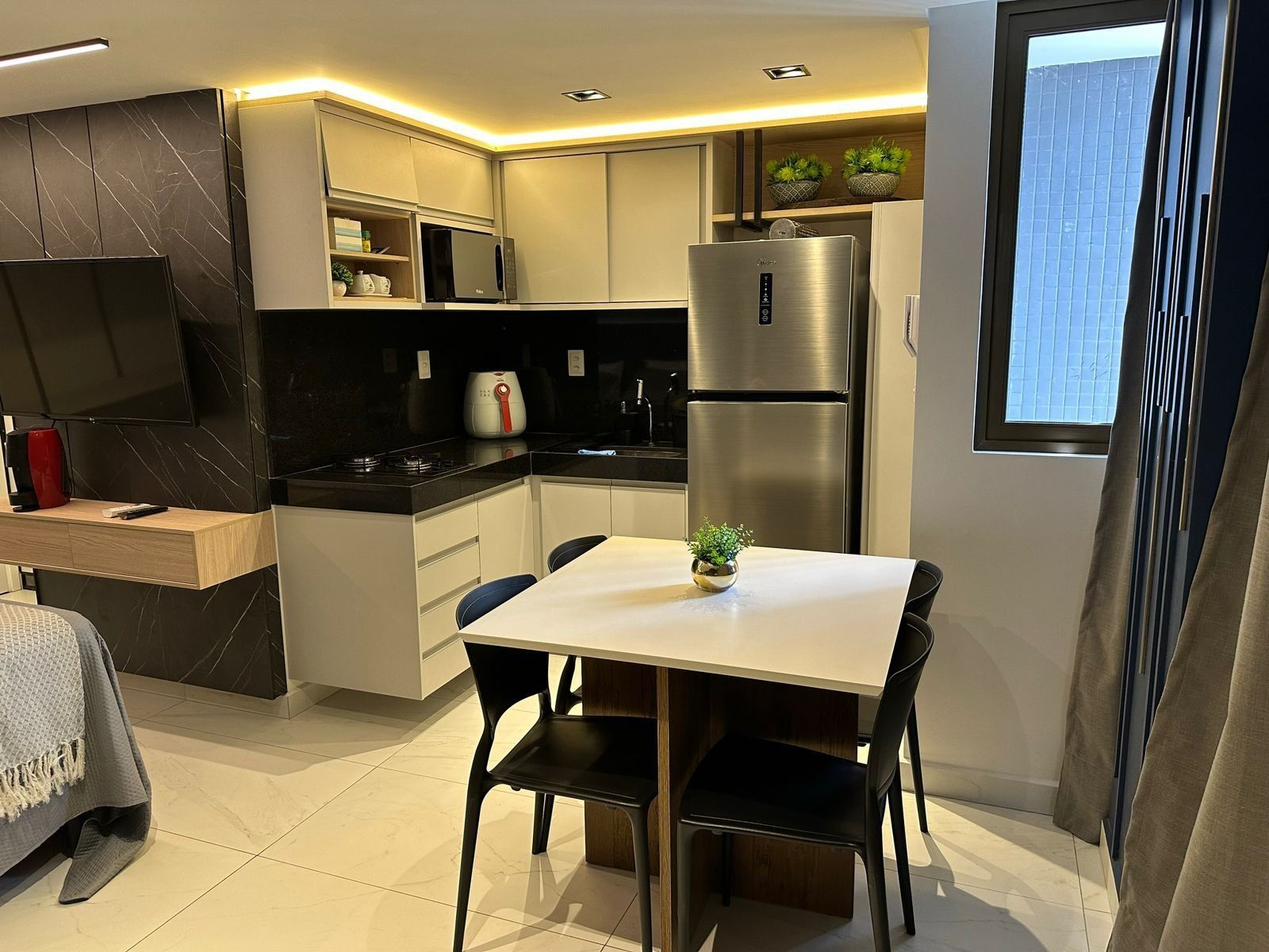 Eine moderne Küche mit Einbauherd, Kühlschrank und Essbereich inklusive Tisch und Stühlen.