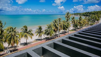 Vista de playa con palmeras, cielo despejado y un camino de baldosas.