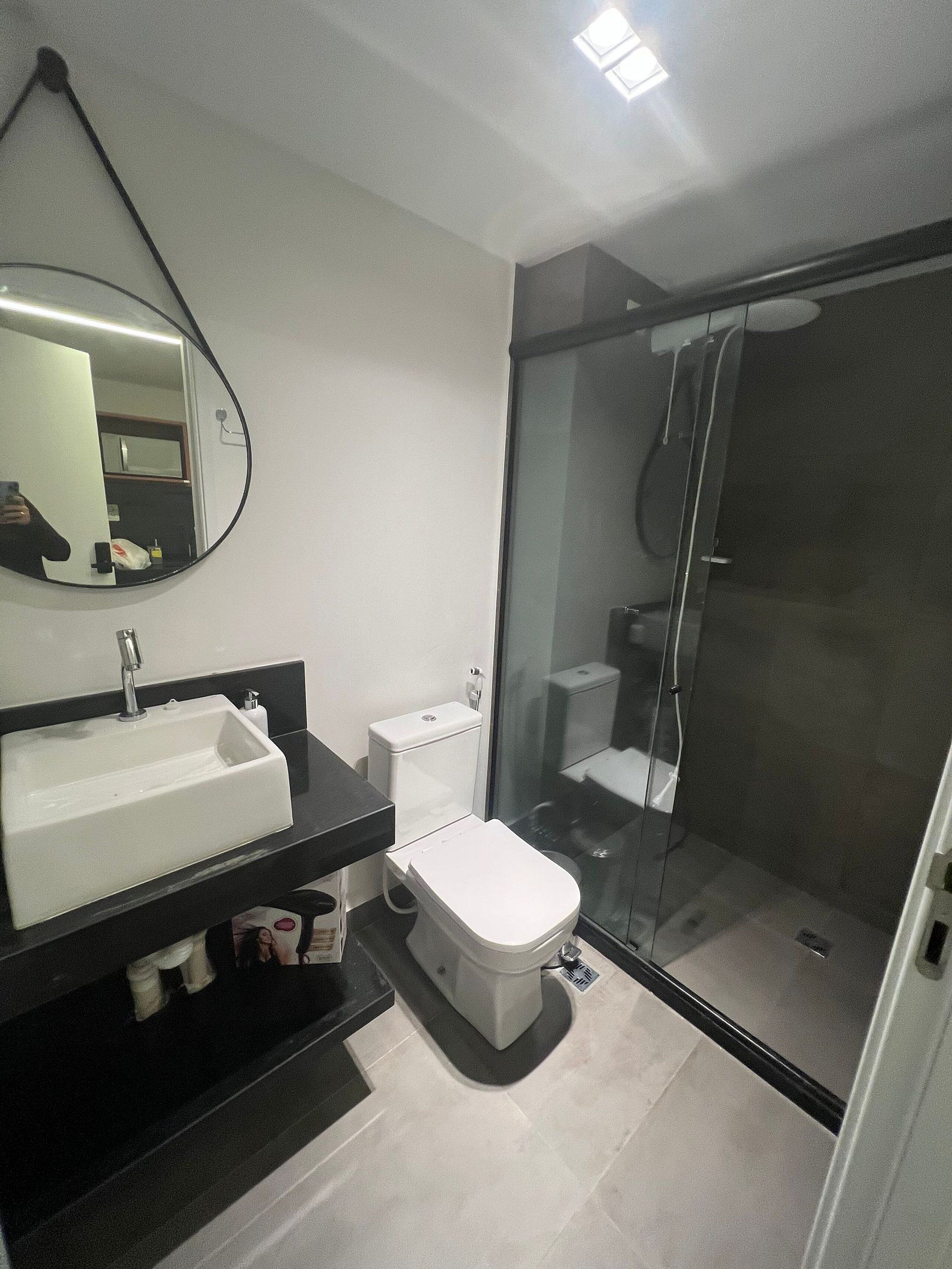 A modern bathroom with a glass-enclosed shower, a white sink, and a toilet.