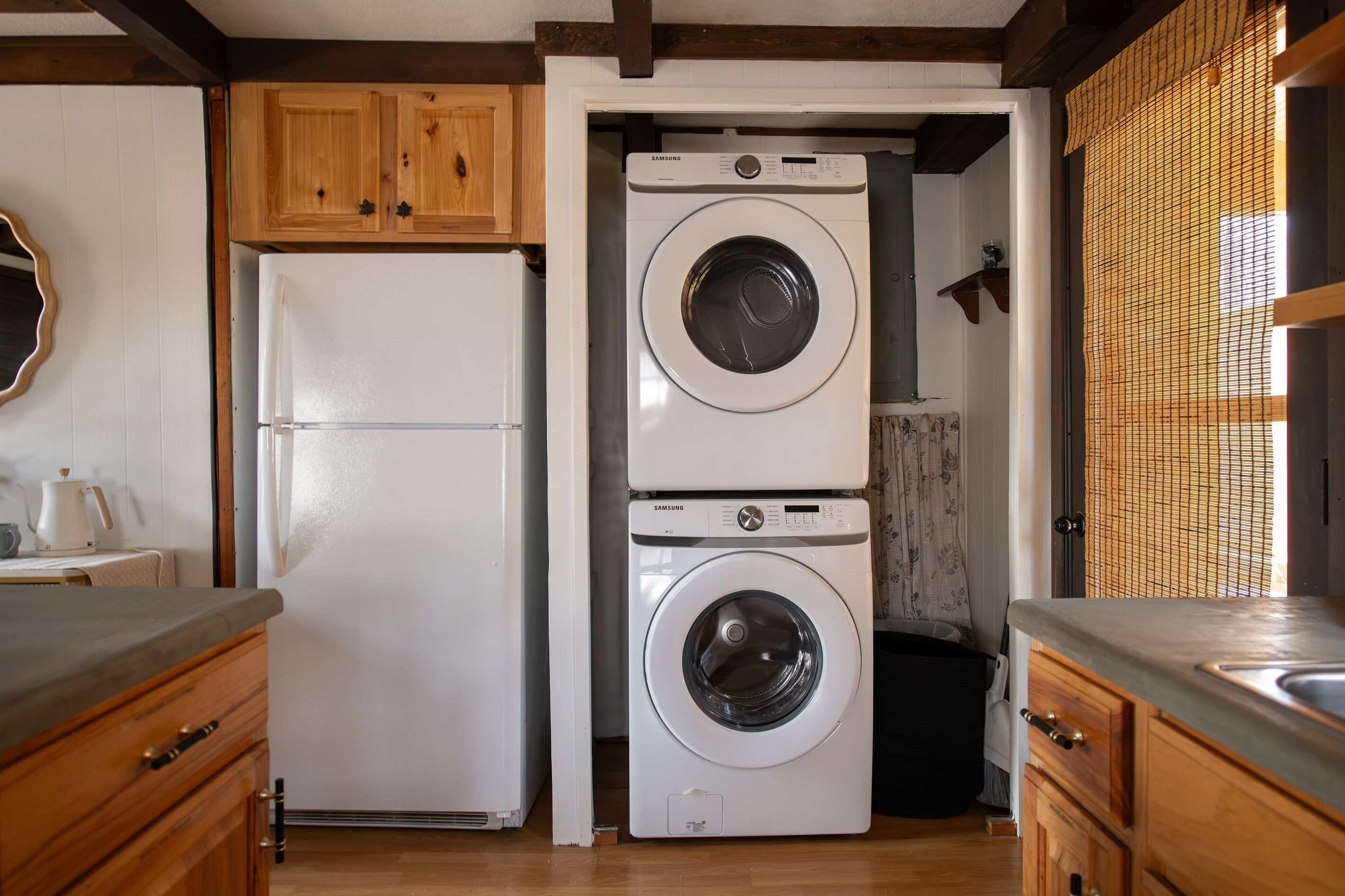 A laundry area with a white washing machine and dryer, wooden cabinets, and a tiled backsplash.