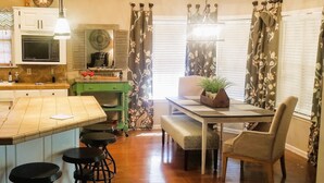A kitchen with a wooden island, bar stools, a dining table with a bench, and a green cabinet.