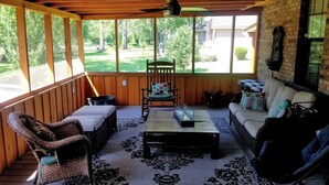 A covered porch with a rocking chair, a sofa, and a coffee table.