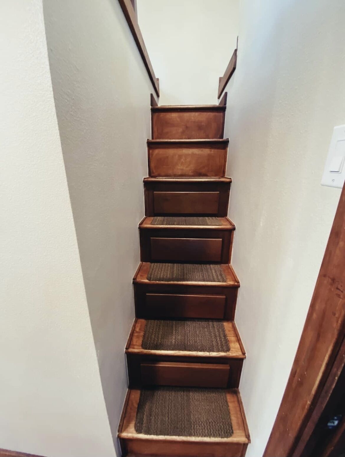 Un escalier étroit avec des marches en bois et une main courante.