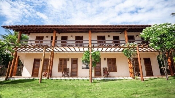 A two-story building with a covered patio area and a flat roof. - Pousada Estrela Peroba (Icapuí)
