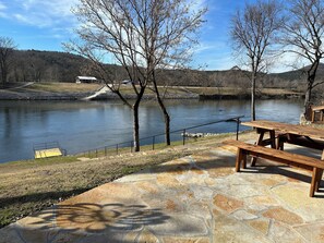 A lakeside patio with stone flooring, wooden picnic tables, and a dock extending into the water. - Marfly Mount Olive Retreat (Melbourne)
