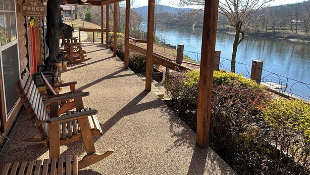 Eine Holzveranda mit Sitzgelegenheiten und Blick auf einen See.