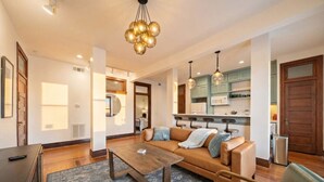 A modern living room with a sofa, coffee table, and a kitchen in the background. - Chic Historic Loft, 3 Blocks from The Strand (Galveston)