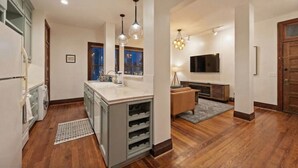 A modern kitchen with a central island, a dining area with a sofa, and a TV mounted on the wall. - Chic Historic Loft, 3 Blocks from The Strand (Galveston)