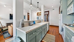 A modern kitchen with a central island, stainless steel appliances, and pendant lighting. - Chic Historic Loft, 3 Blocks from The Strand (Galveston)