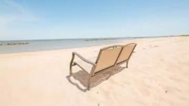 A beach with a single empty beach chair. -  One minute walk to the Beach -Norfolk (Norfolk)